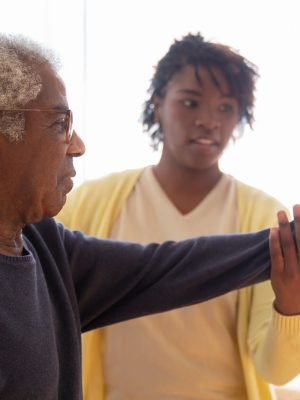 A caregiver guiding a senior man through gentle exercises at home